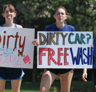 High School Band Students holding up signs advertising a free car wash